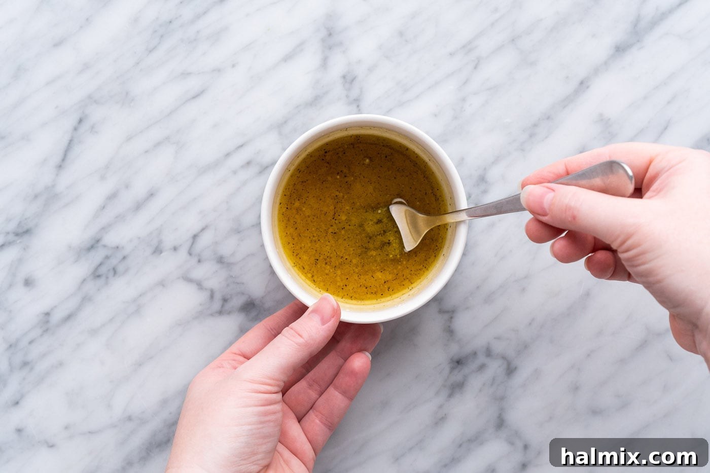 Whisking lemon dressing in a small bowl with a fork