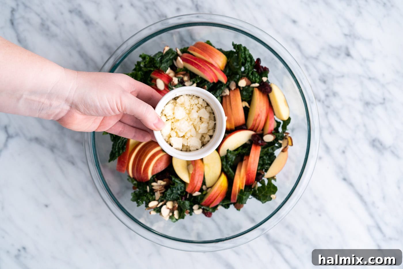 Adding crumbled feta to kale salad