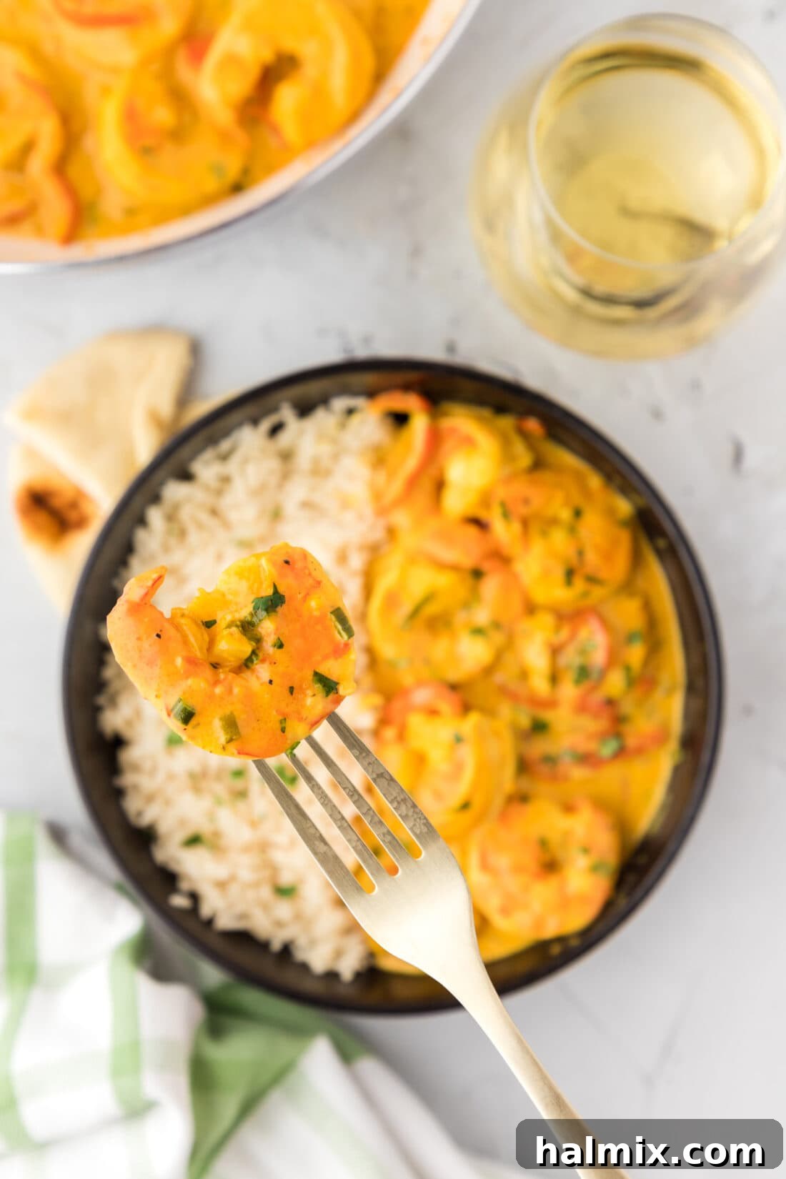 Vibrant Shrimp Curry 2 A fork holding a piece of juicy shrimp and a bell pepper, hovering over a bowl of creamy shrimp curry served with fluffy white rice.