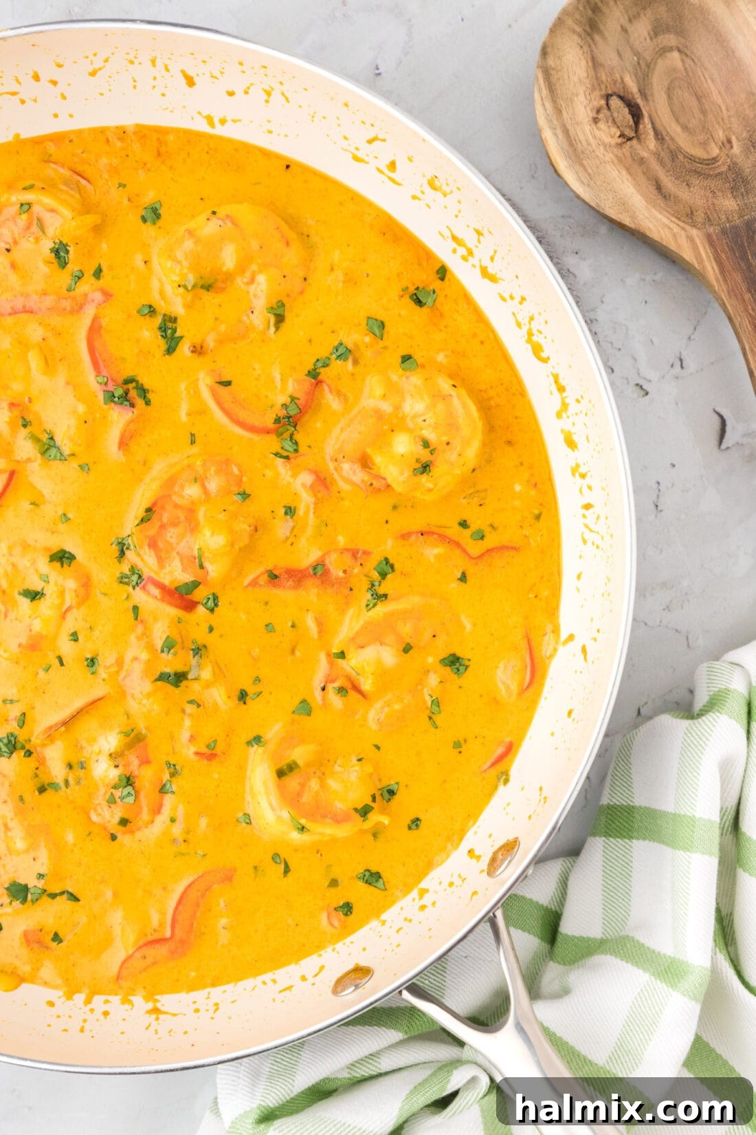 Vibrant Shrimp Curry 3 Close-up view of vibrant shrimp curry simmering in a large stainless steel skillet, showcasing the rich, creamy sauce and colorful vegetables.