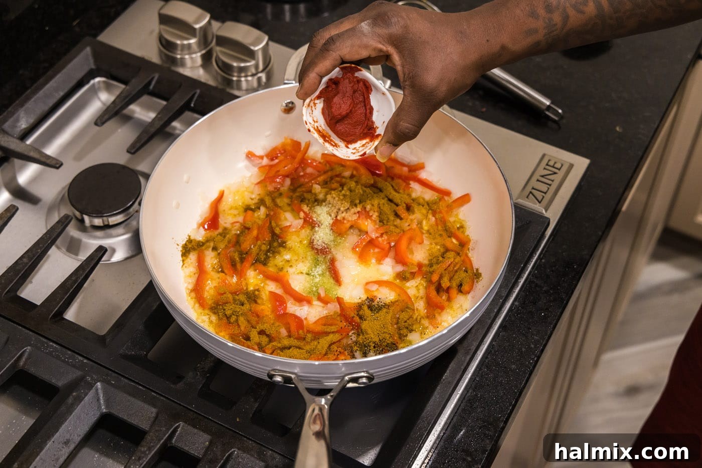 adding tomato paste to skillet with garlic and vegetables