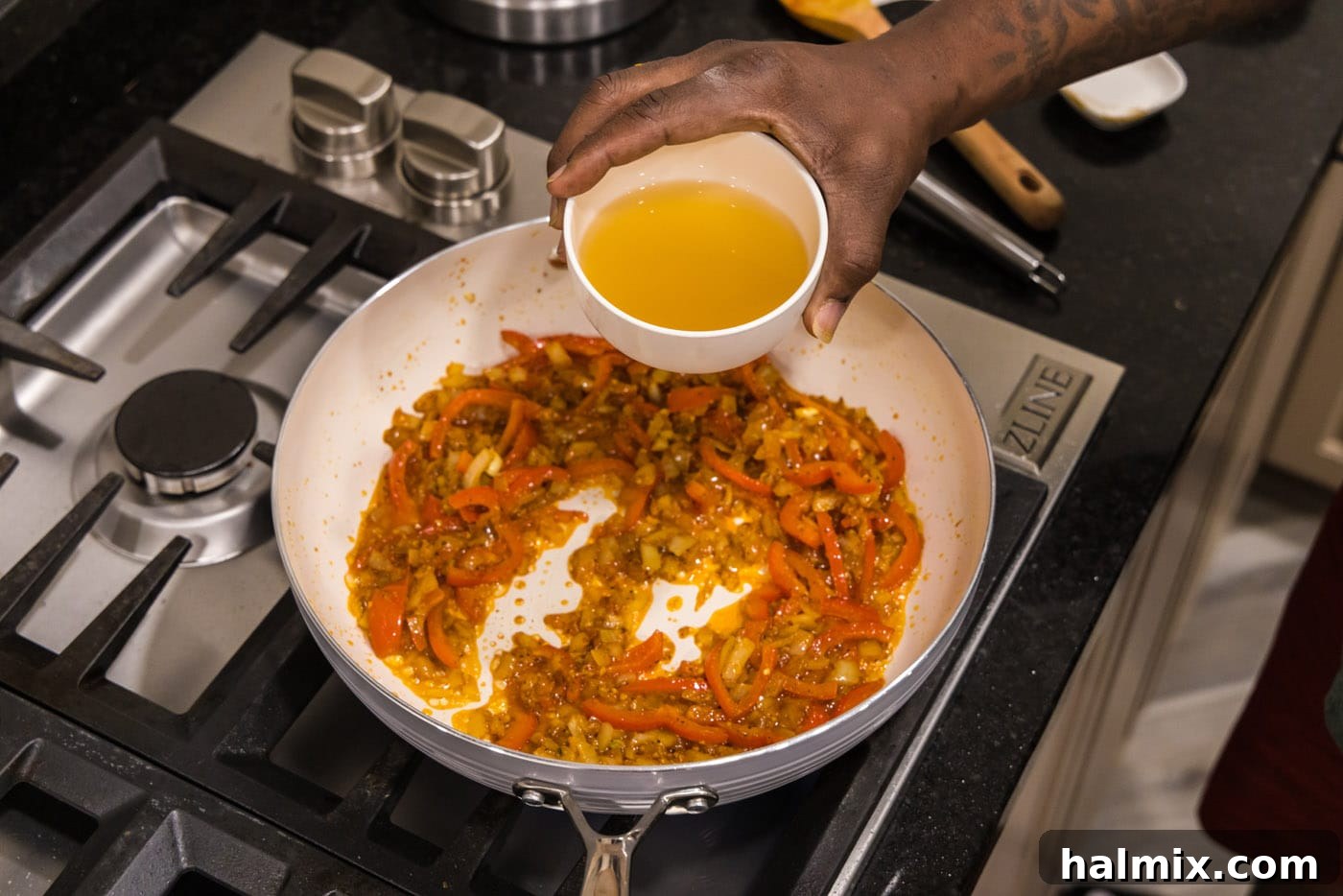 Vibrant Shrimp Curry 7 adding chicken stock to curry in a skillet