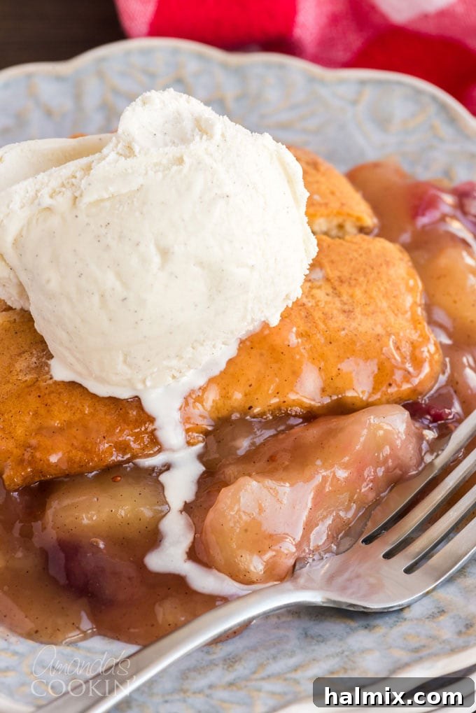 Slice of warm Apple Cranberry Crisp with melting vanilla ice cream on top, ready to be served for a delightful fall dessert.