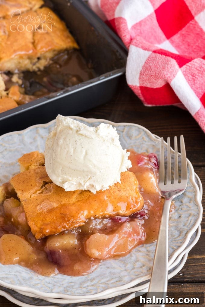 Close-up of a slice of Apple Cranberry Crisp topped with a scoop of vanilla ice cream, showing the bubbly fruit filling and crisp topping.