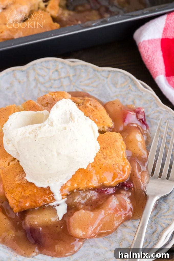 Full pan of Apple Cranberry Crisp with scoops of vanilla ice cream melting on top, garnished with a few fresh cranberries.