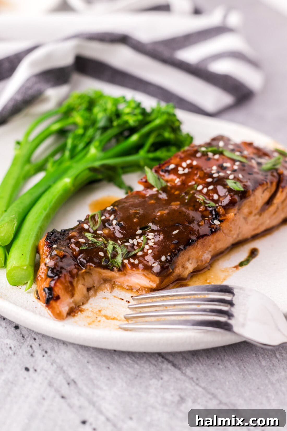 A slice taken out of a teriyaki salmon fillet on a plate, showing the tender, flaky interior