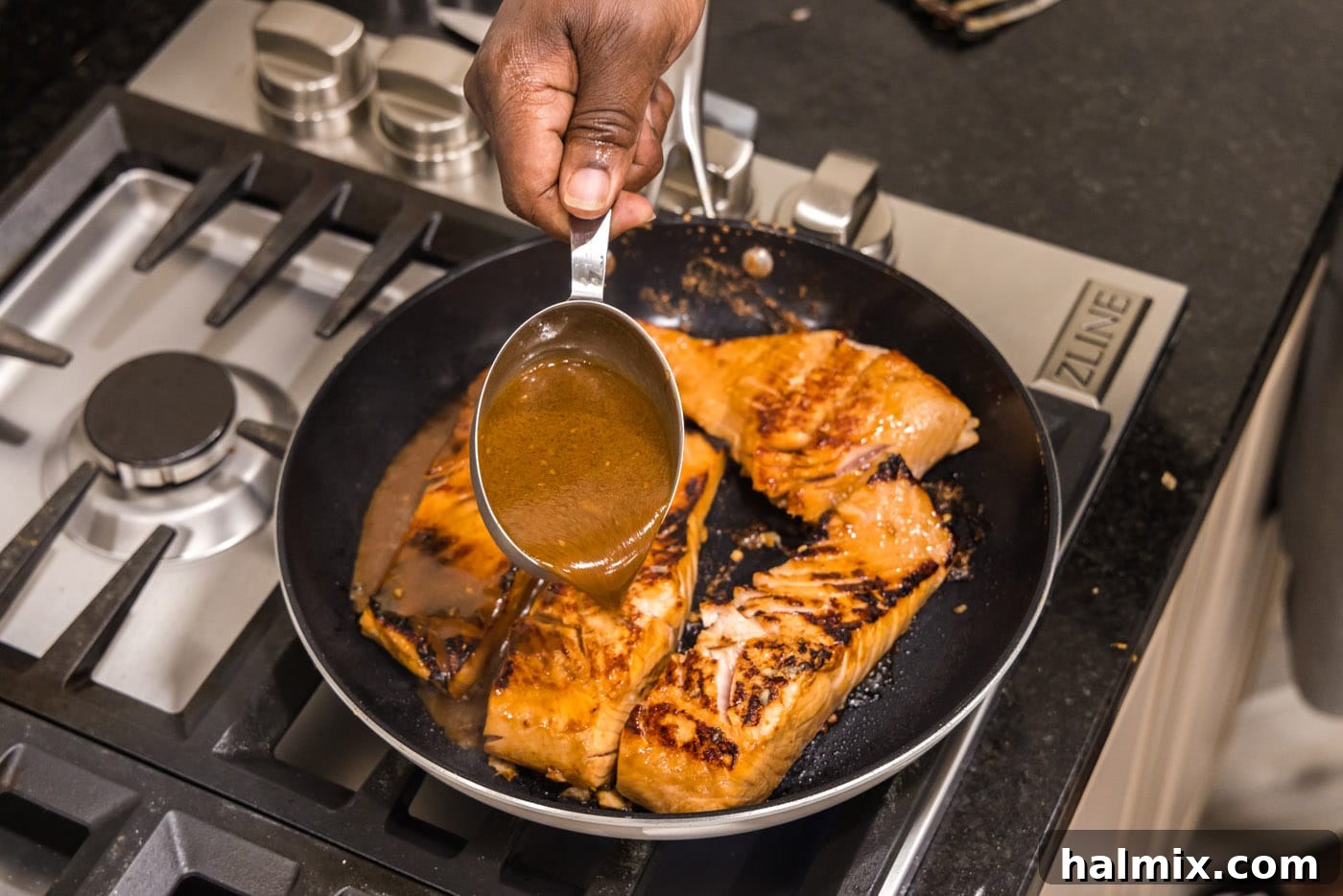 Pouring thickened teriyaki glaze over pan-seared salmon
