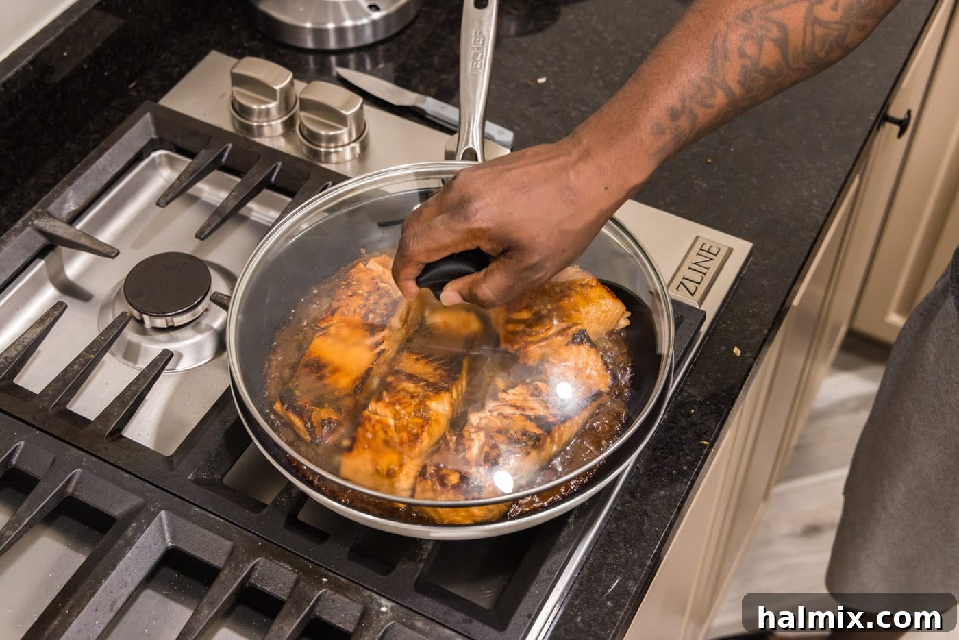 Lid placed on skillet of teriyaki salmon on the stovetop to finish cooking