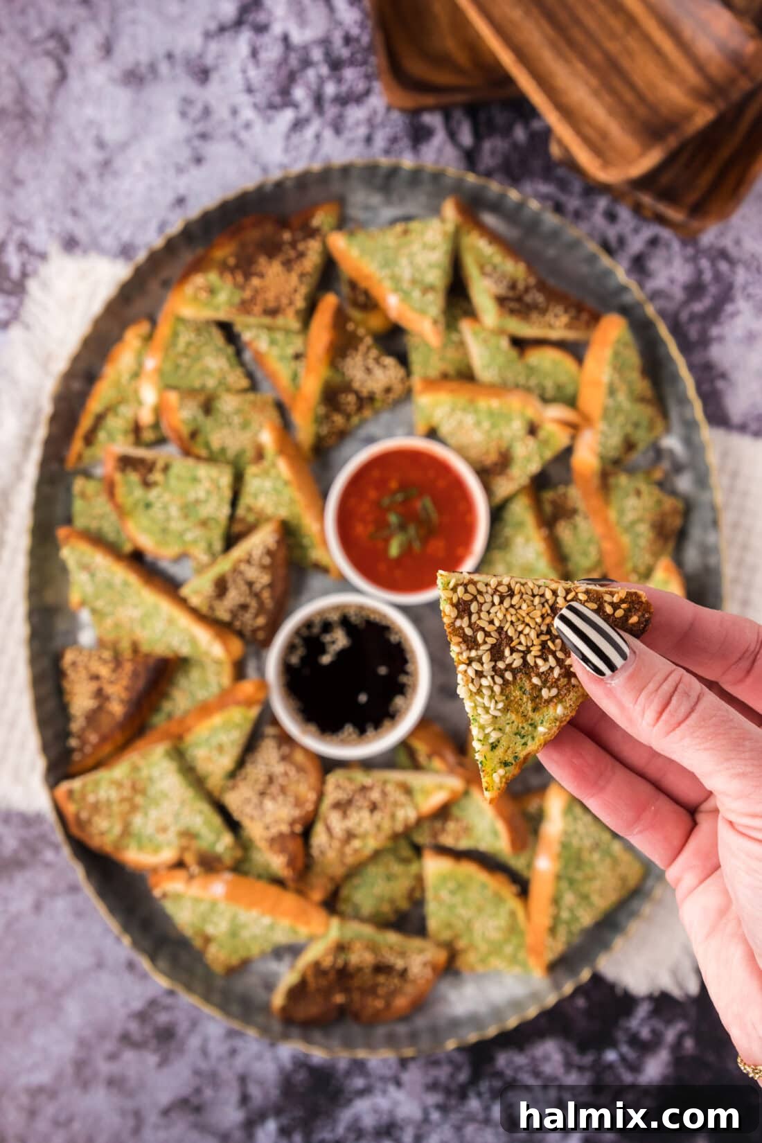 Crispy Golden Shrimp Toast 2 Crispy Pan-Fried Shrimp Toast held aloft, with a platter of more shrimp toast in the background