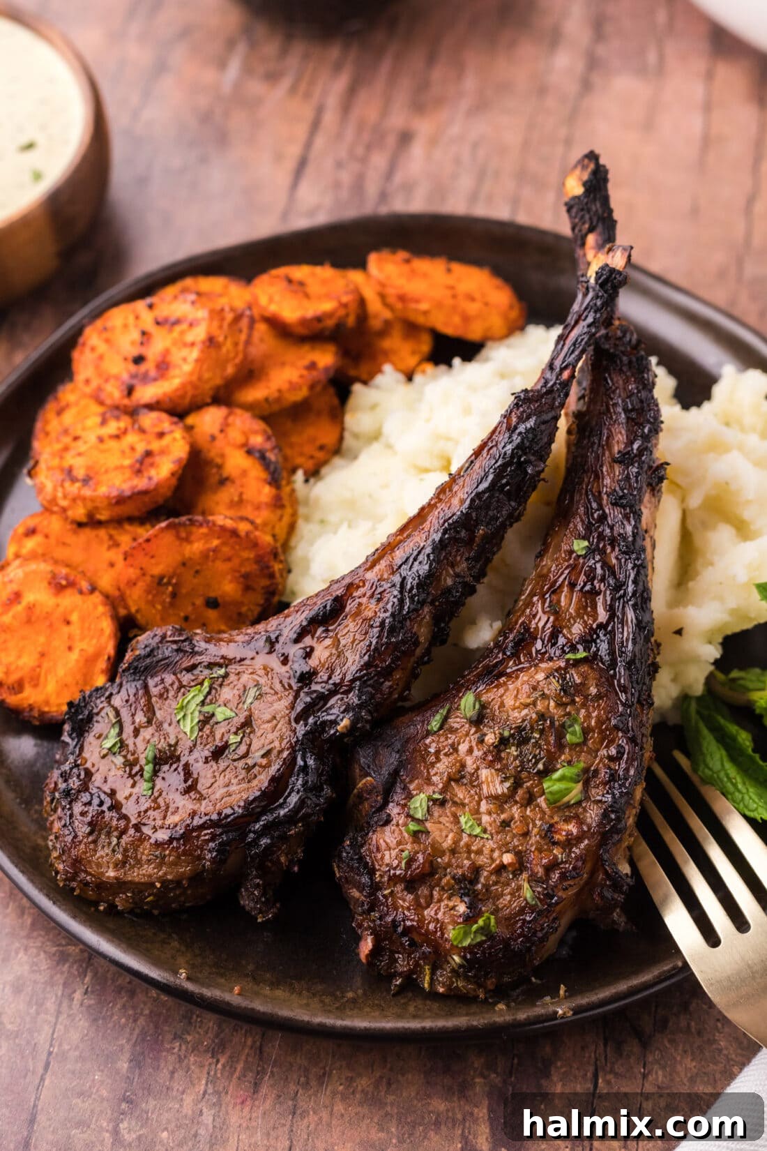Two Broiled Lamb Chops on a plate with vibrant carrots and creamy mashed potatoes, showcasing a beautiful crust