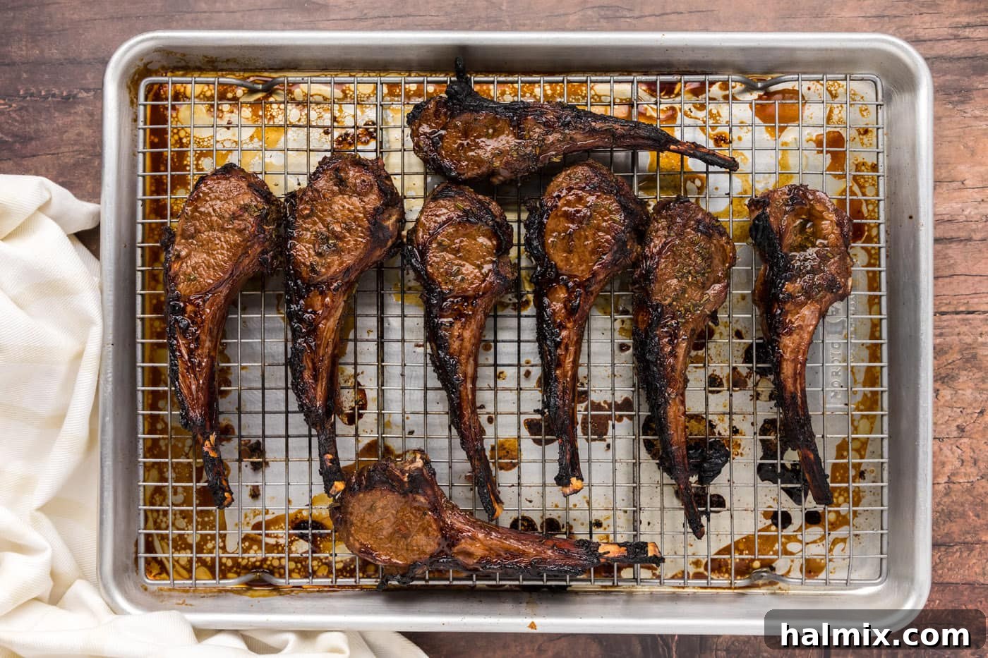 Succulent broiled lamb chops resting on a baking sheet after being removed from the oven, showing the crispy crust.