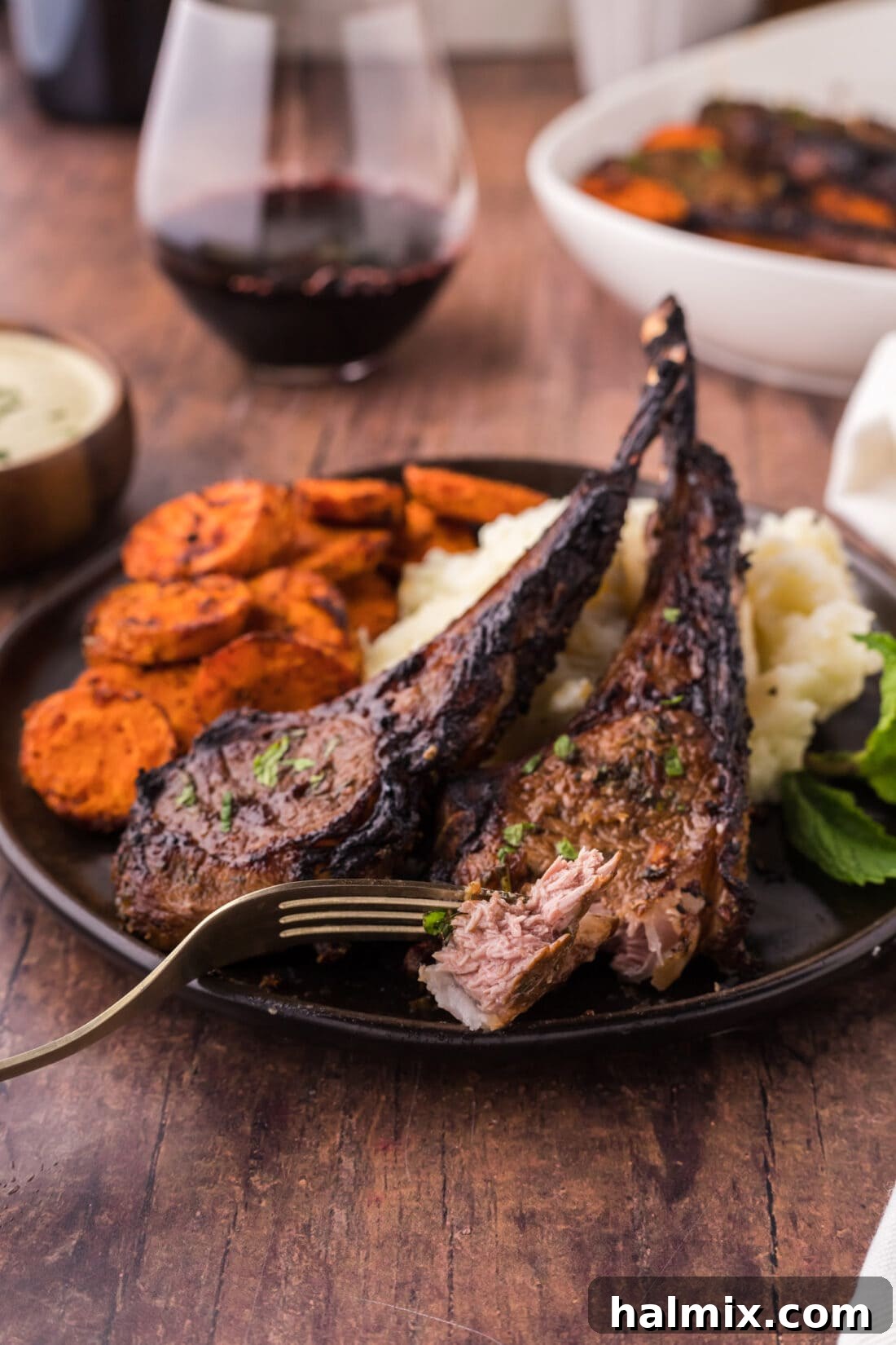 A close-up of a broiled lamb chop piece on a fork, showing its tender interior and crispy exterior, ready to be enjoyed.