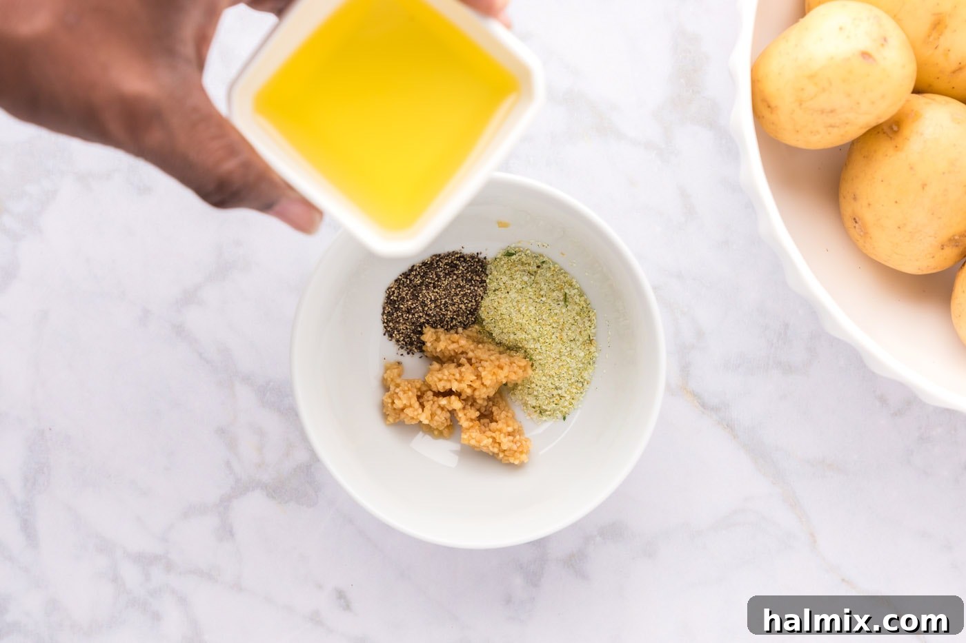 adding olive oil to garlic and seasonings in bowl