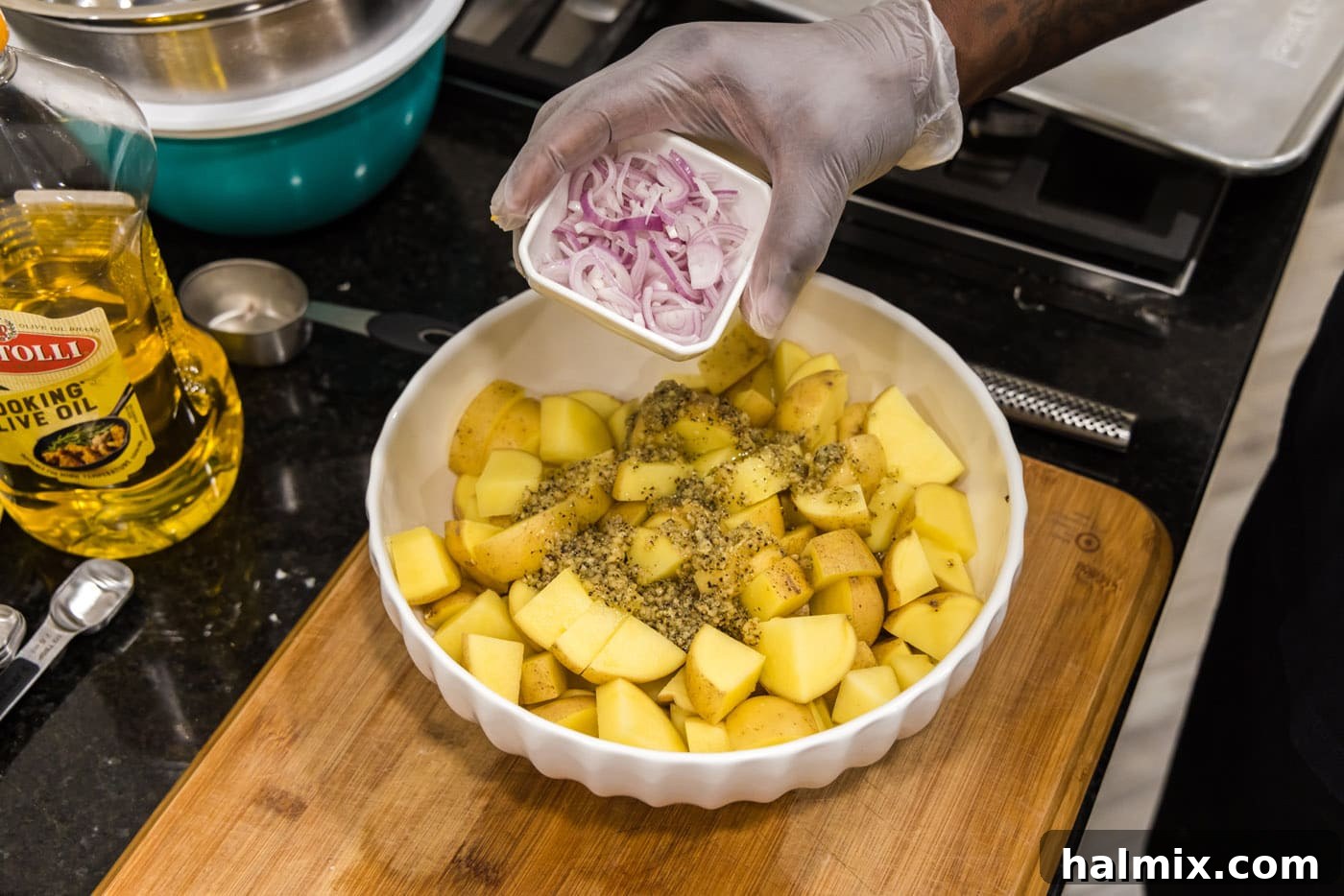 adding shallots to cubed potatoes in a bowl