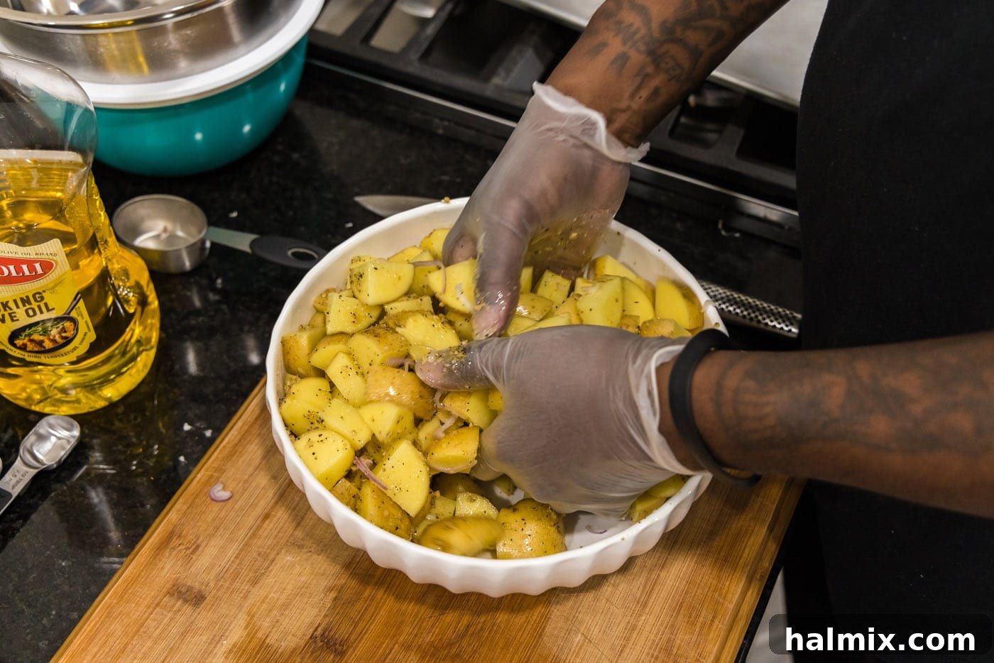 hands mixing cubed potatoes in a bowl