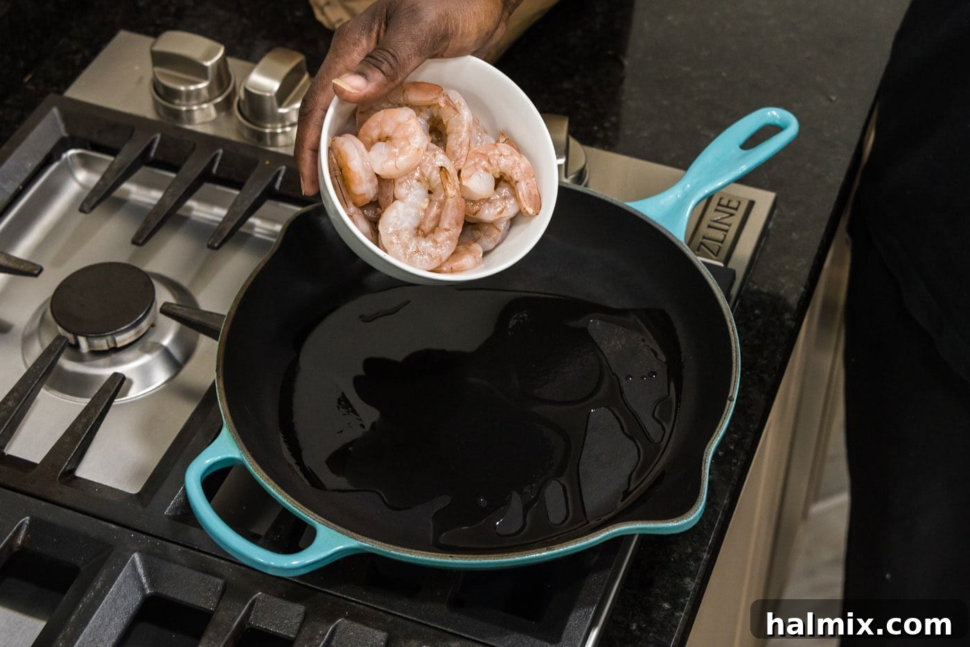 Adding seasoned shrimp to a hot skillet with olive oil