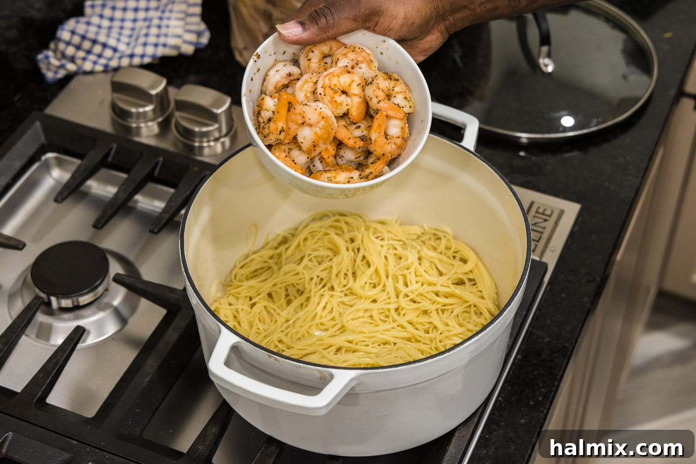 Adding sautéed shrimp to the pot of pasta