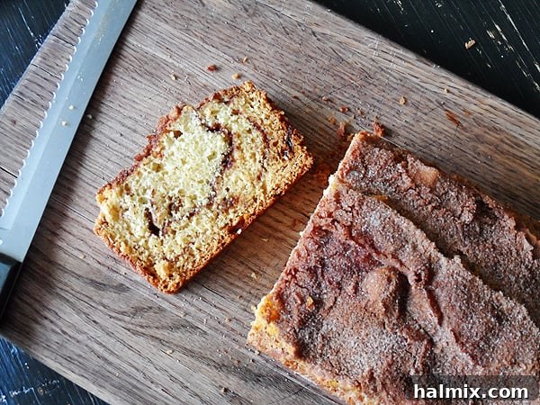 Aromatic Cinnamon Raisin Swirl Loaf 5 A beautifully sliced loaf of cinnamon raisin swirl quick bread, showcasing the distinct layers of cinnamon sugar and plump raisins, on a wooden cutting board.