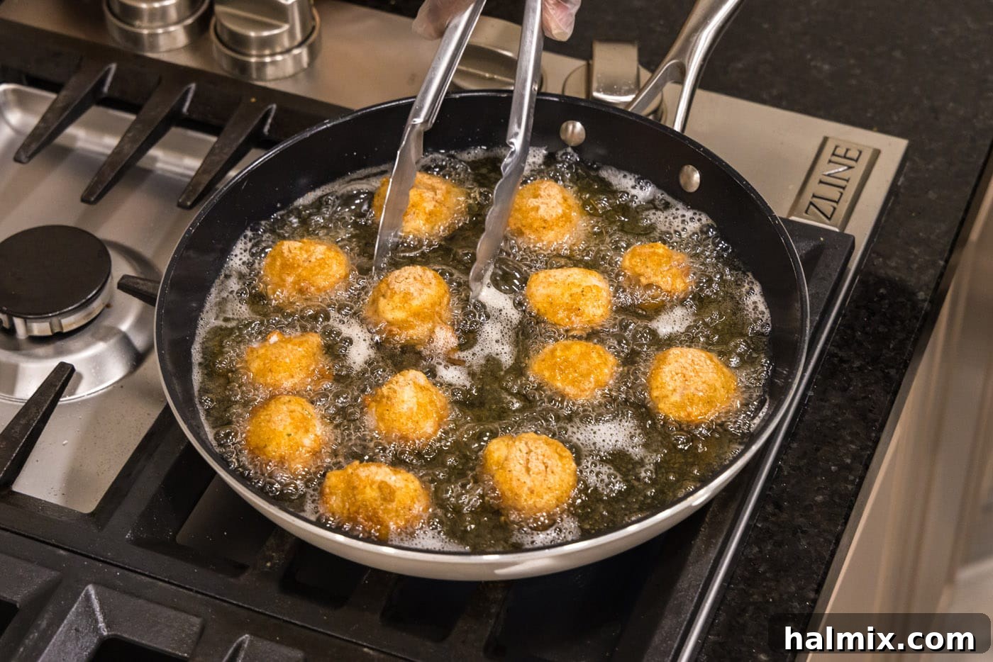 Golden Seared Scallops 12 tongs turning scallops in a skillet of oil