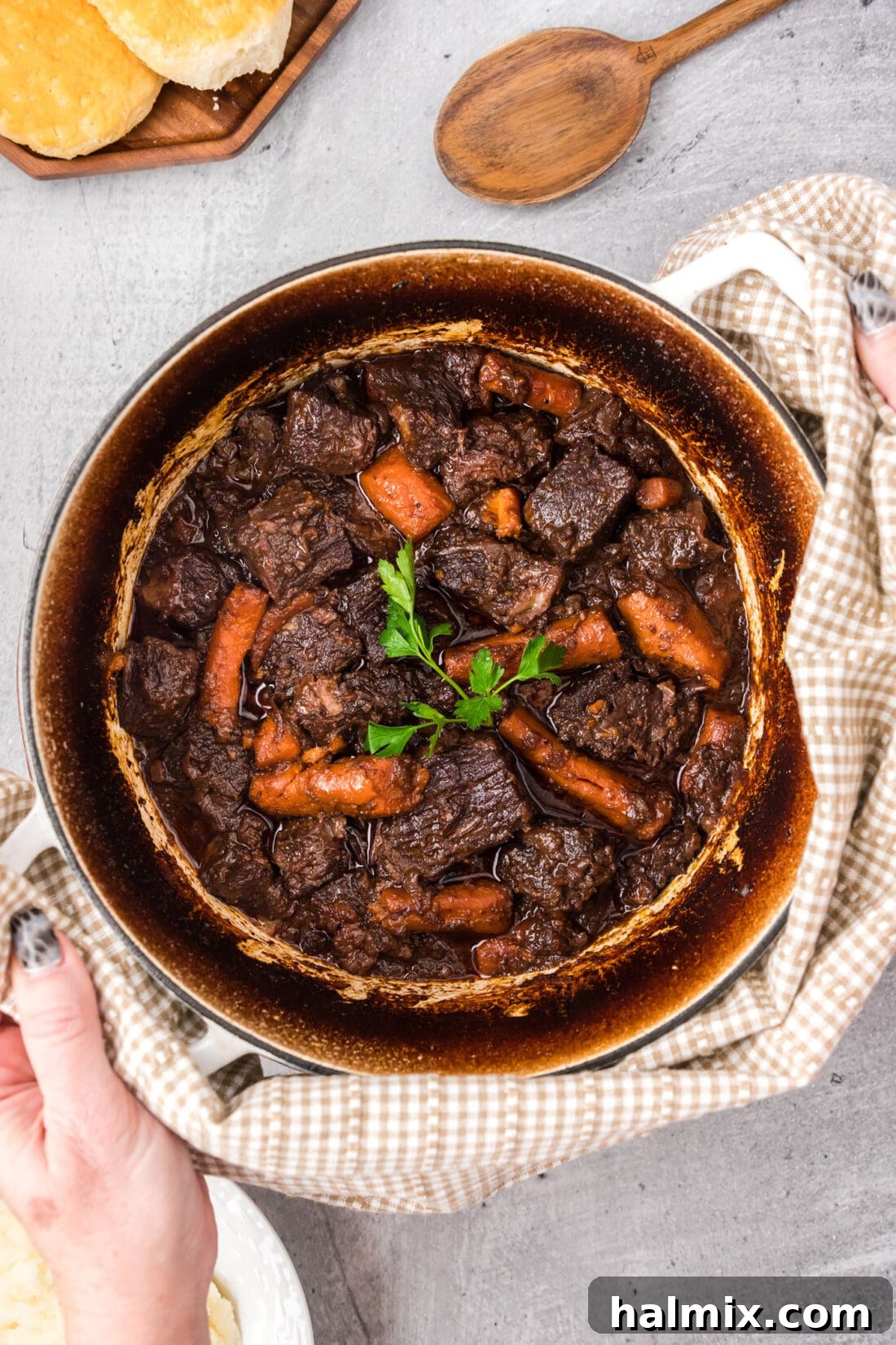 Hands holding a hot pot of Braised Beef with a towel