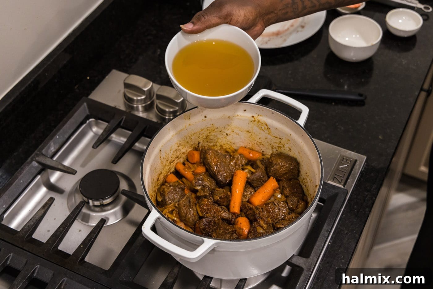 adding chicken stock to braised beef