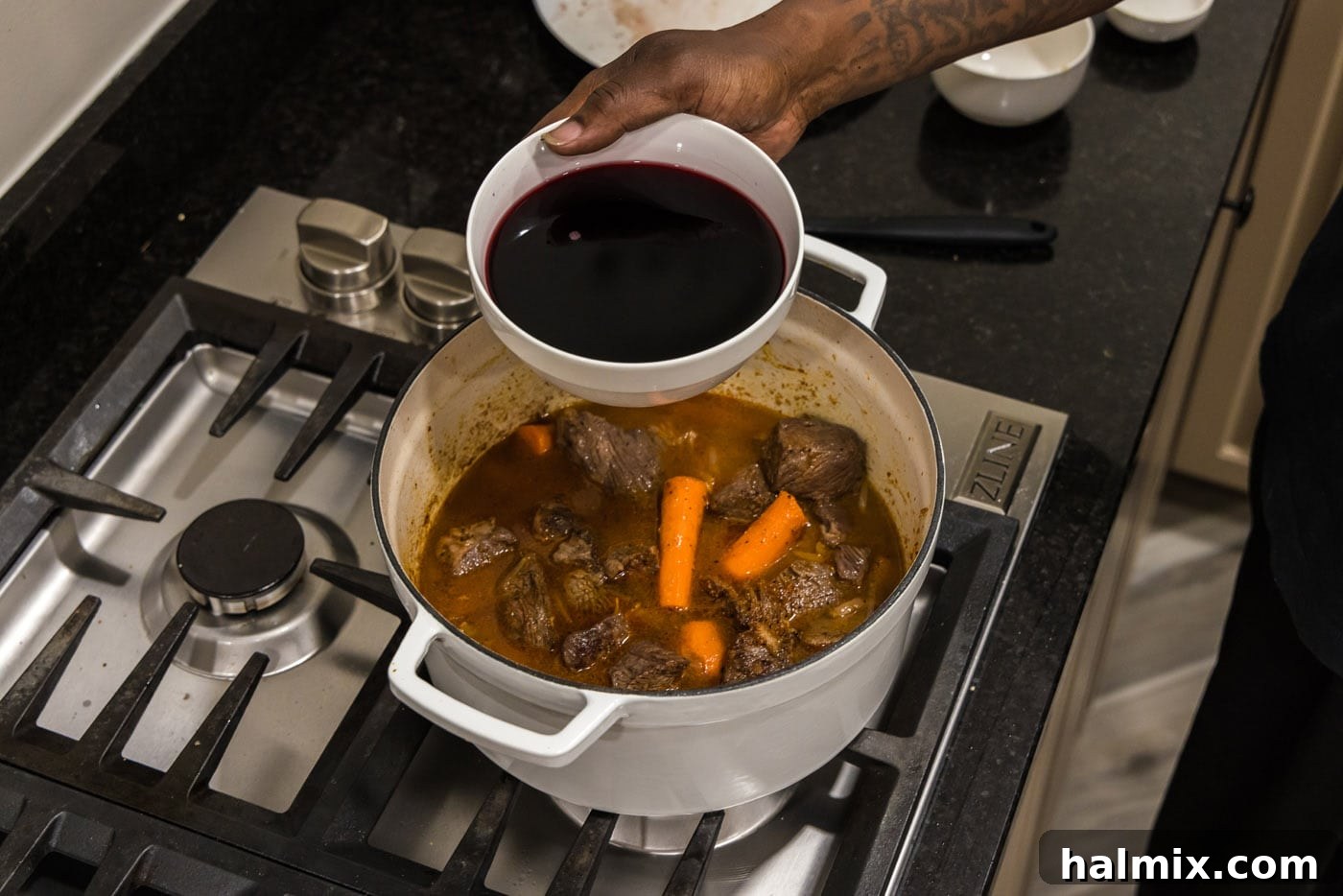red wine added to braised beef in a dutch oven