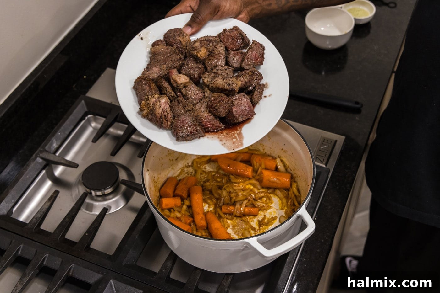 adding beef back to dutch oven with carrots and onions