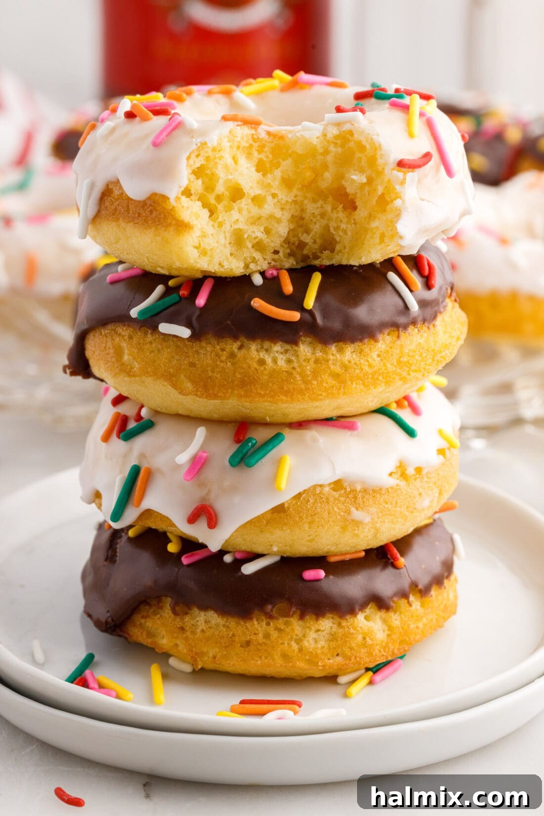 Easy Cake Mix Donuts 2 Cake Mix Donut with a bite taken out sitting on top of a stack of three Cake Mix Donuts