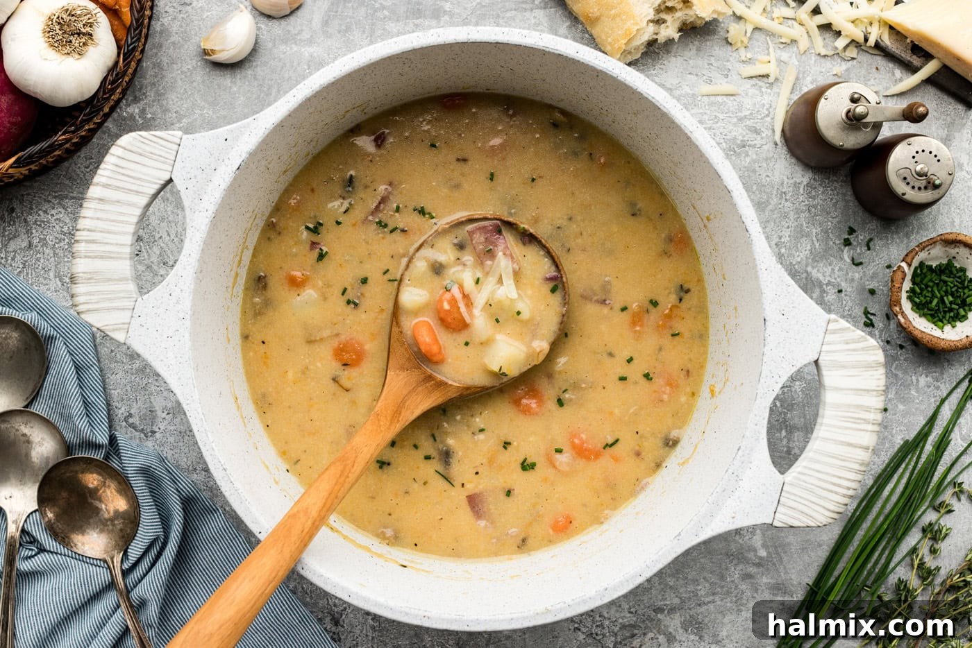 Dutch oven with garlic potato soup, ladled with a wooden spoon