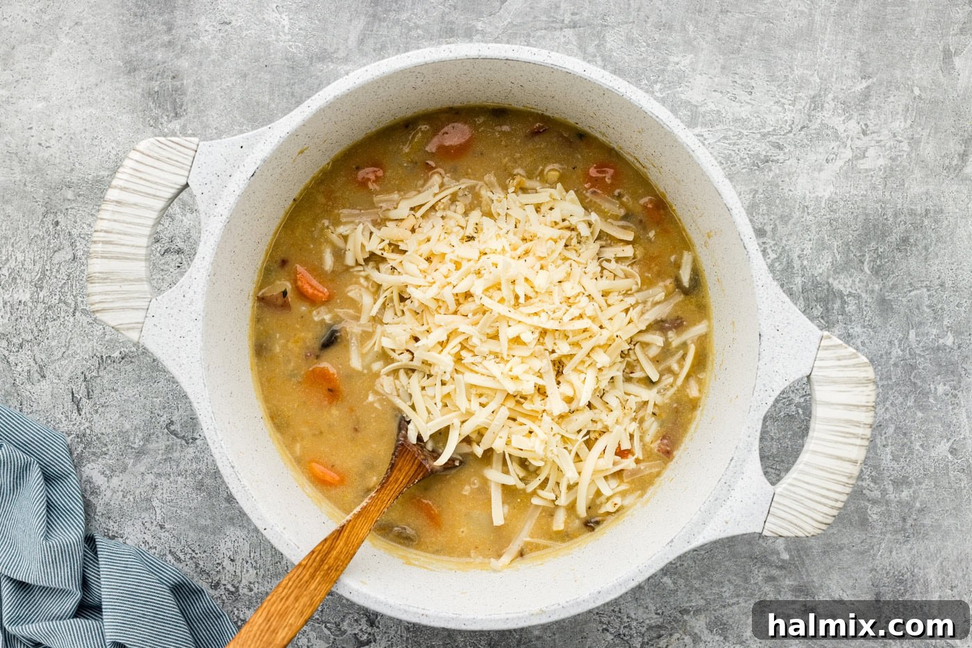 shredded cheese added to garlic potato soup in a Dutch oven