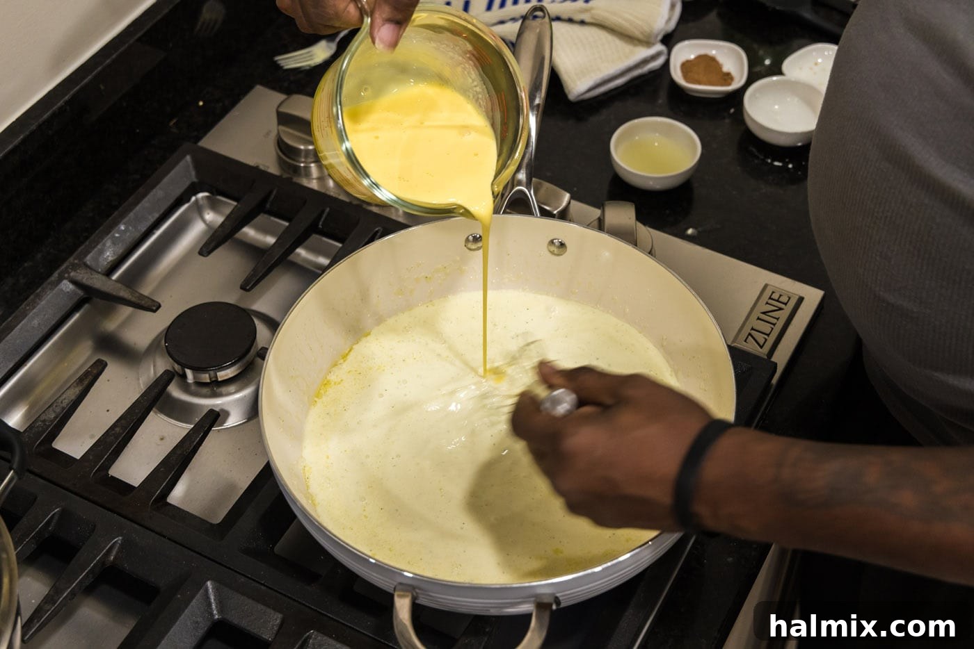 tempering egg mixture in a pan with cream