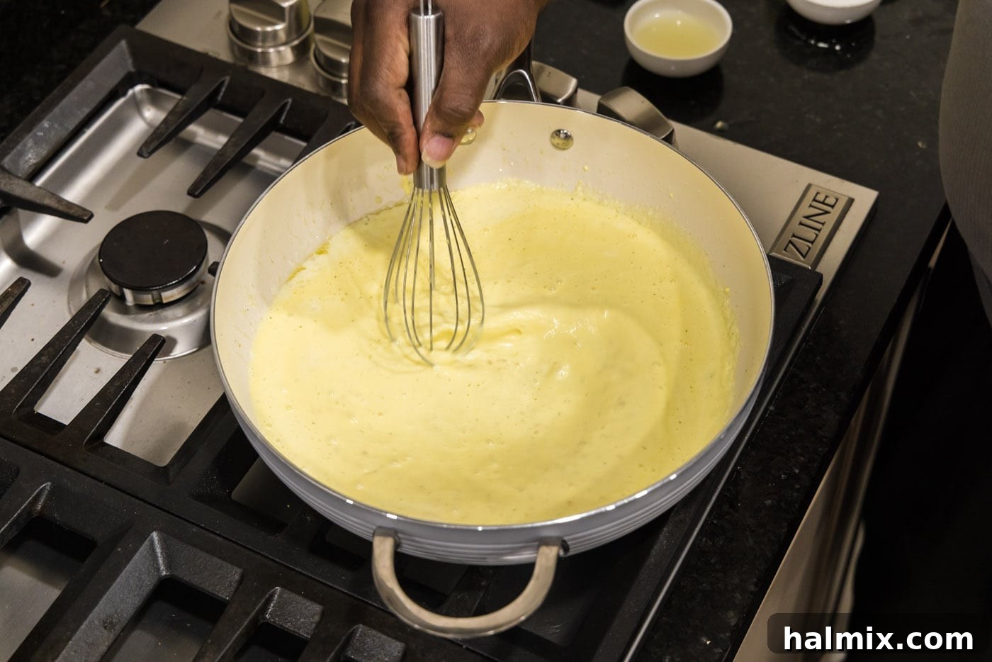whisking egg mixture into cream in a hot skillet