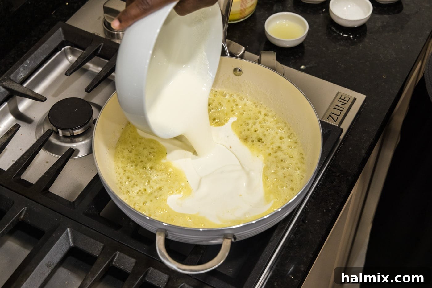 pouring heavy cream into skillet with garlic butter mixture