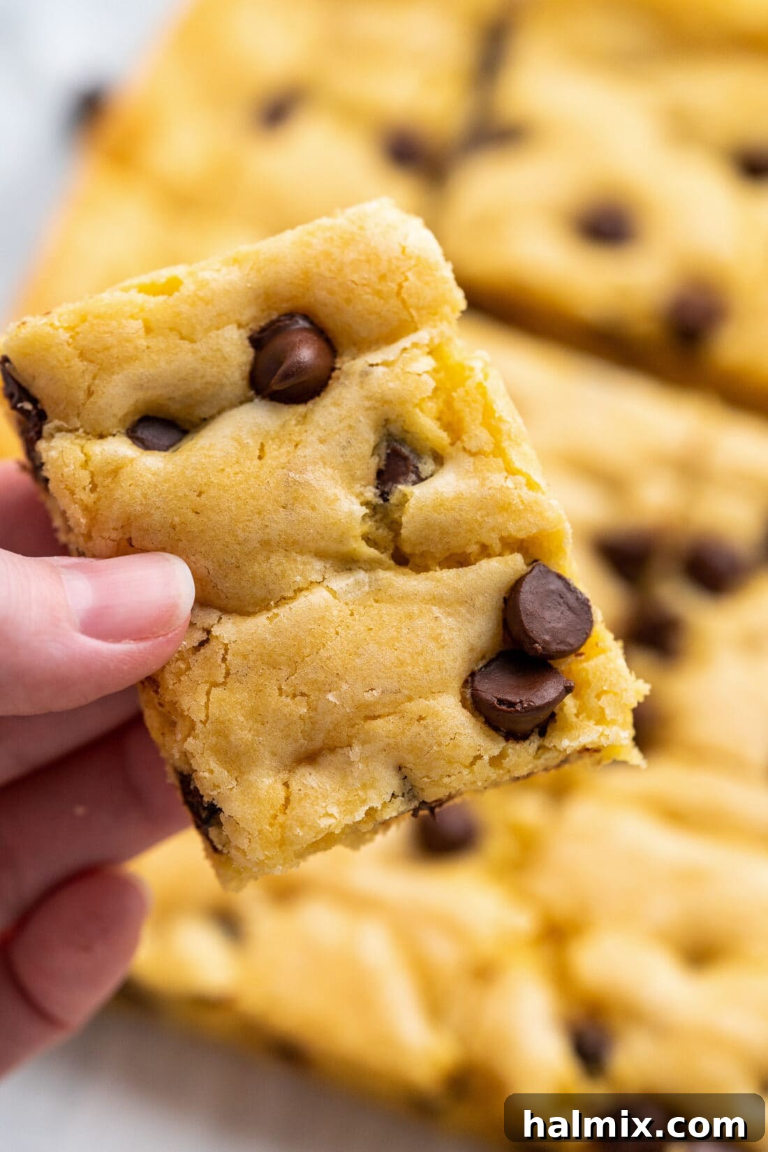 Easy Cake Mix Cookie Bars 13 A hand presenting a single Cake Mix Cookie Bar, showcasing its perfect size and delicious appearance.