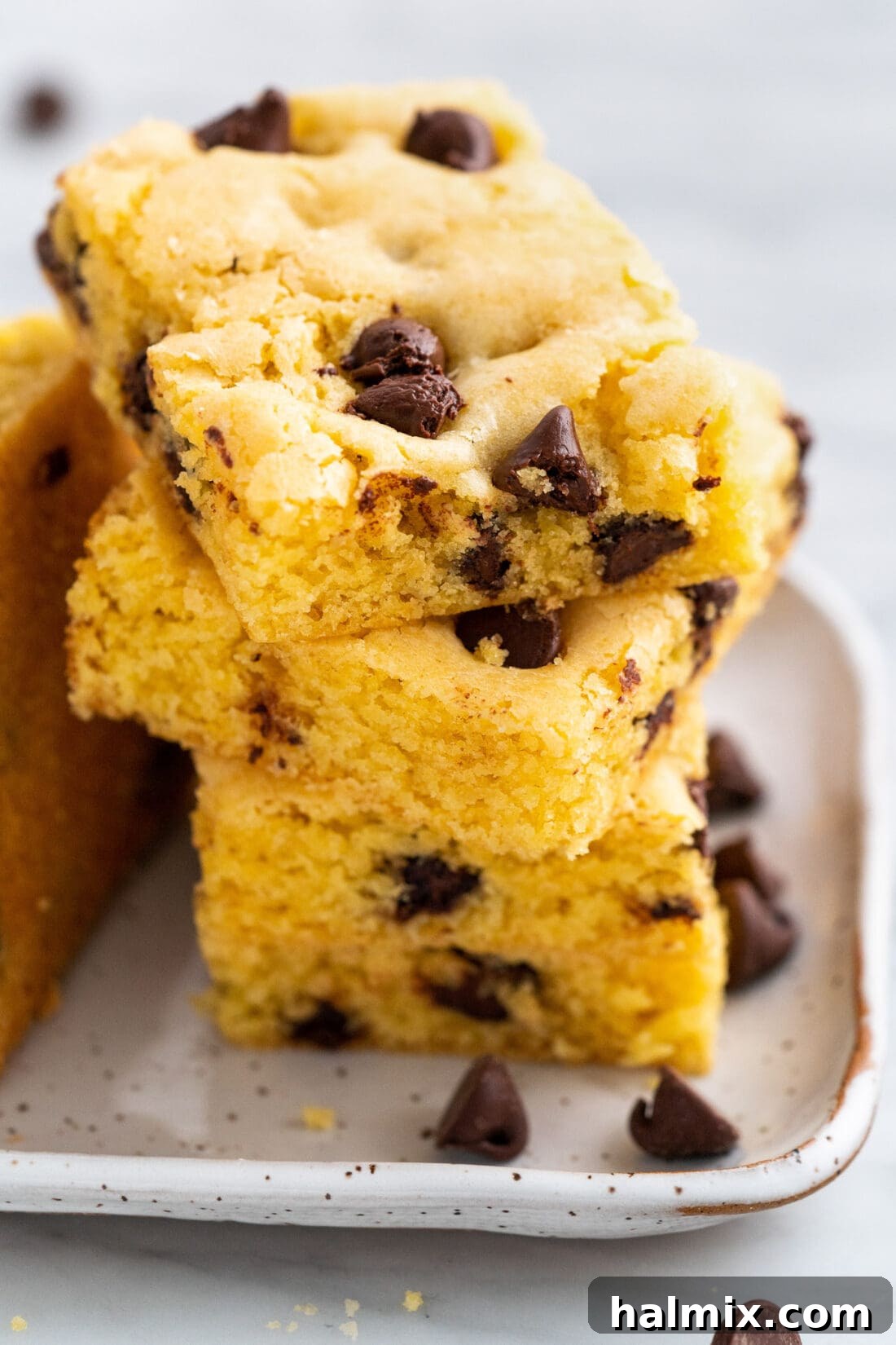 Easy Cake Mix Cookie Bars 3 A stack of golden-brown Cake Mix Cookie Bars, showcasing their chewy texture and embedded chocolate chips.