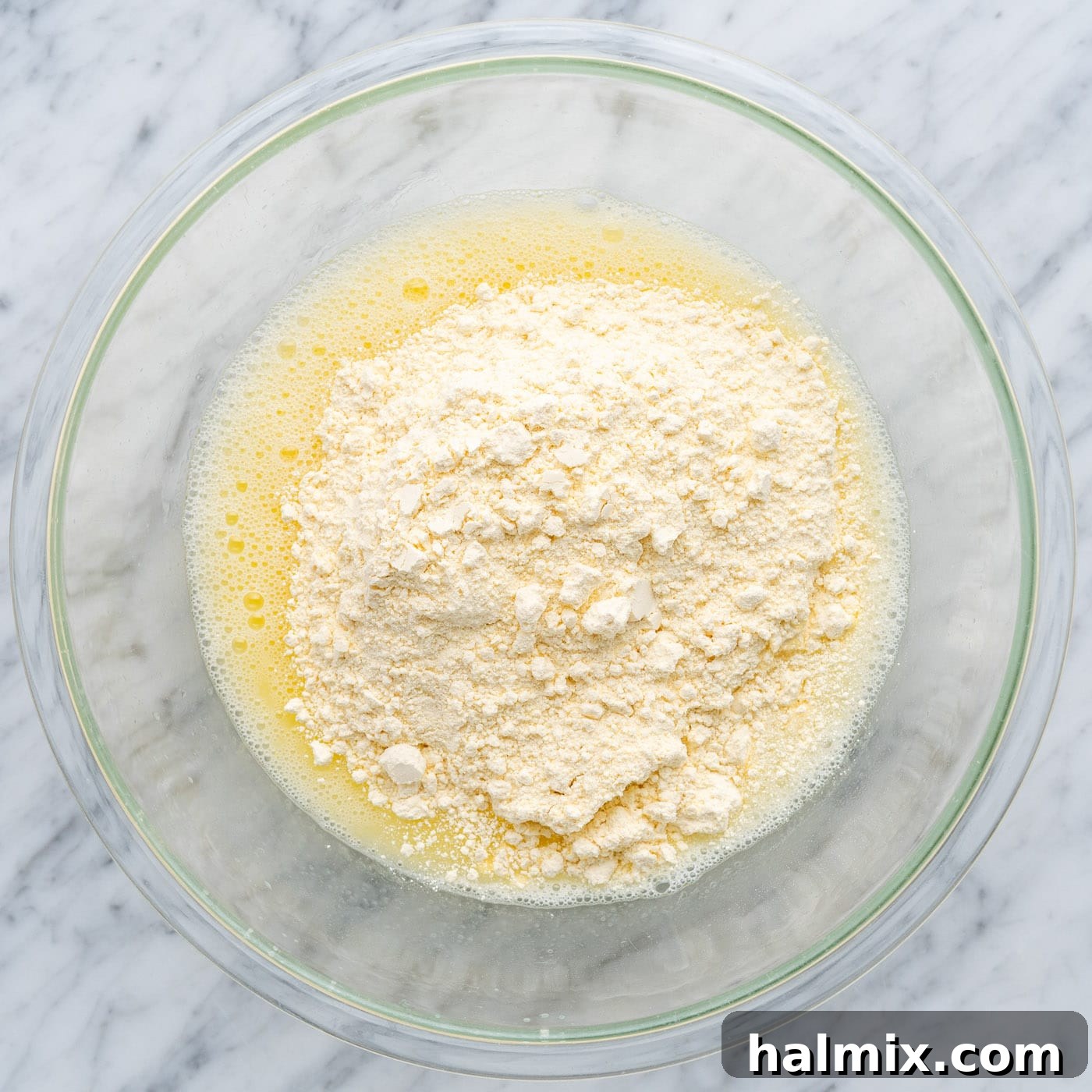Easy Cake Mix Cookie Bars 6 Adding yellow cake mix powder to the bowl containing whisked water, egg, and oil.
