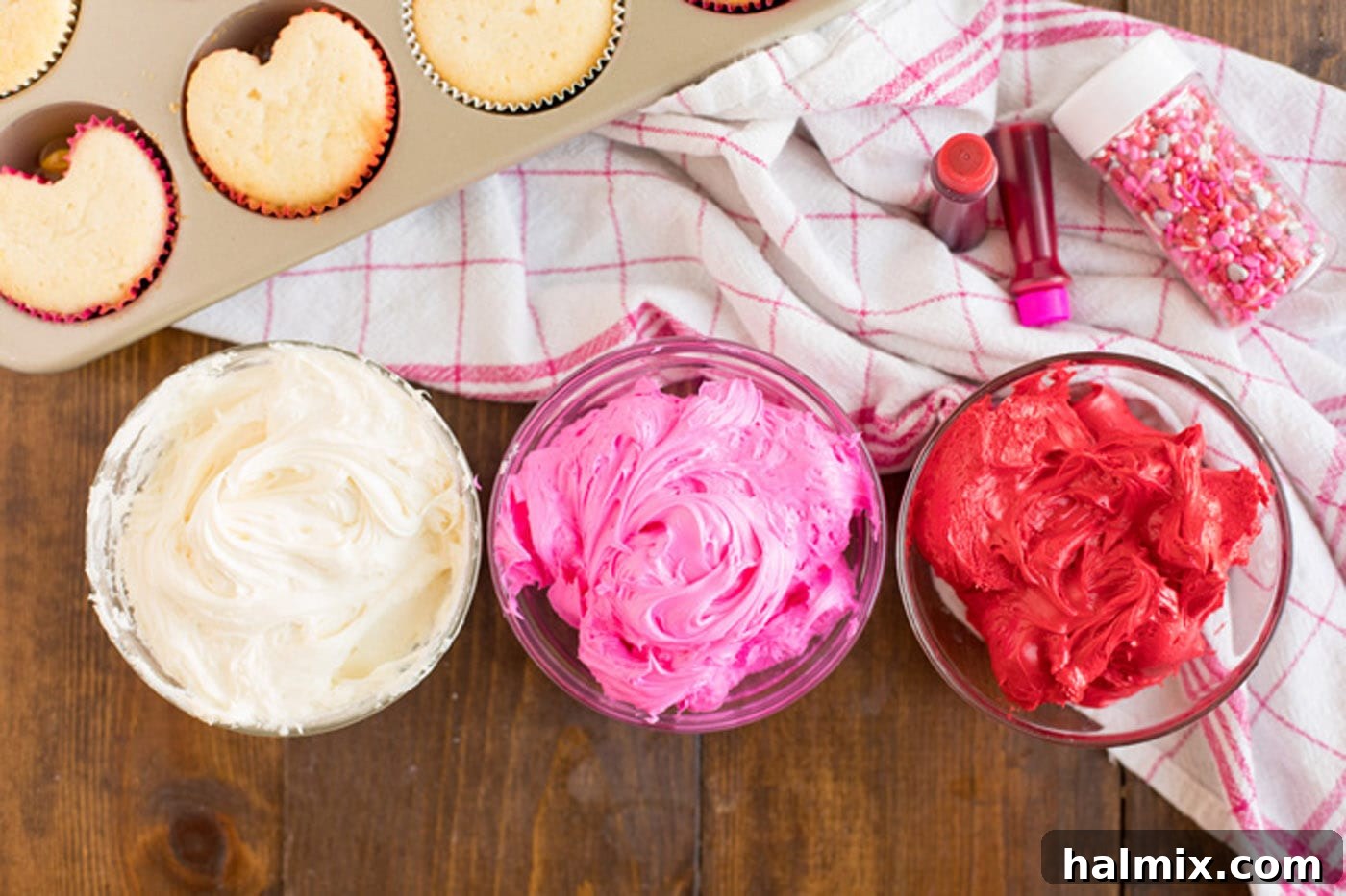 Three bowls of white, pink, and red frosting.