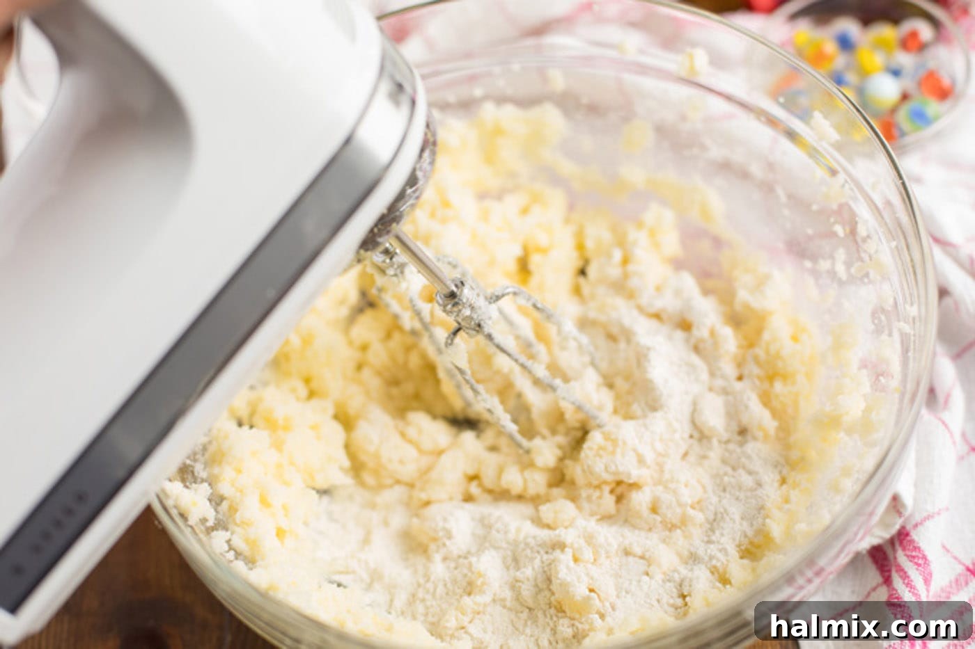 Hand mixer blending cupcake batter together in a bowl.
