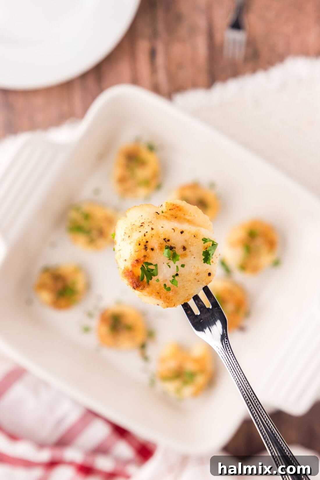 Lemon Garlic Baked Scallops 2 Close up of a Baked Scallop on a seafood fork, showing its golden crust and delicious topping.