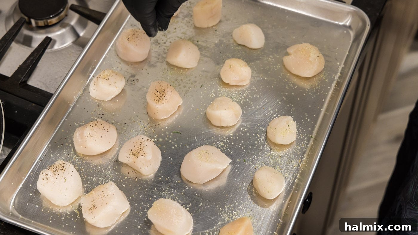 Lemon Garlic Baked Scallops 6 A hand sprinkling garlic salt and pepper over fresh scallops.