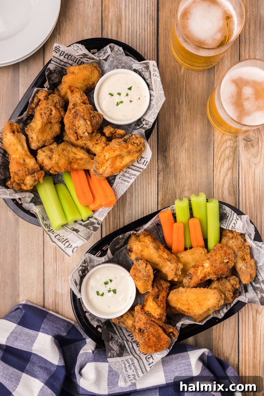 Two baskets of Crispy Fried Chicken Wings with carrots, celery, and ranch for dipping.