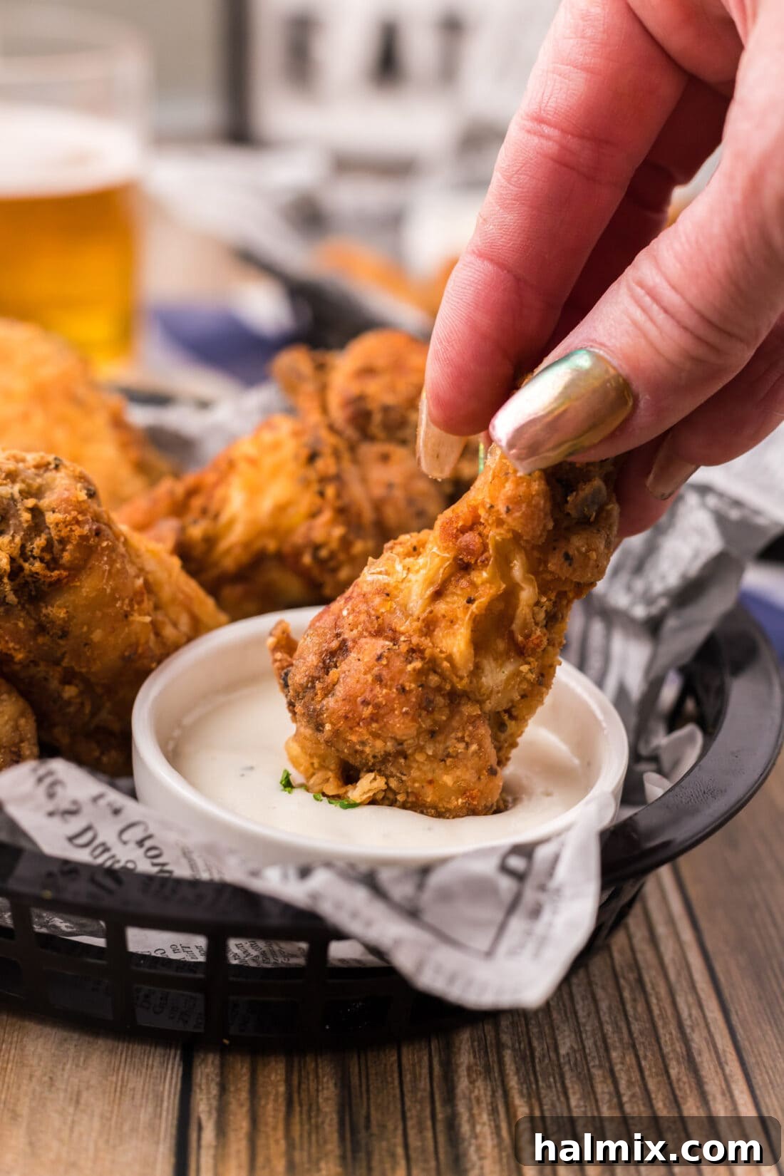 A Fried Chicken Wing being dipped into a bowl of creamy ranch dressing.