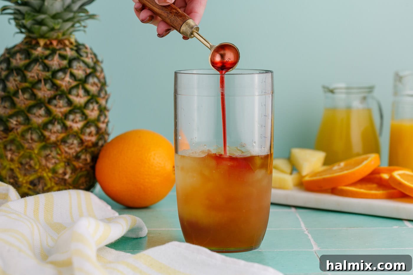 adding grenadine to cocktail glass with rum and liqueur