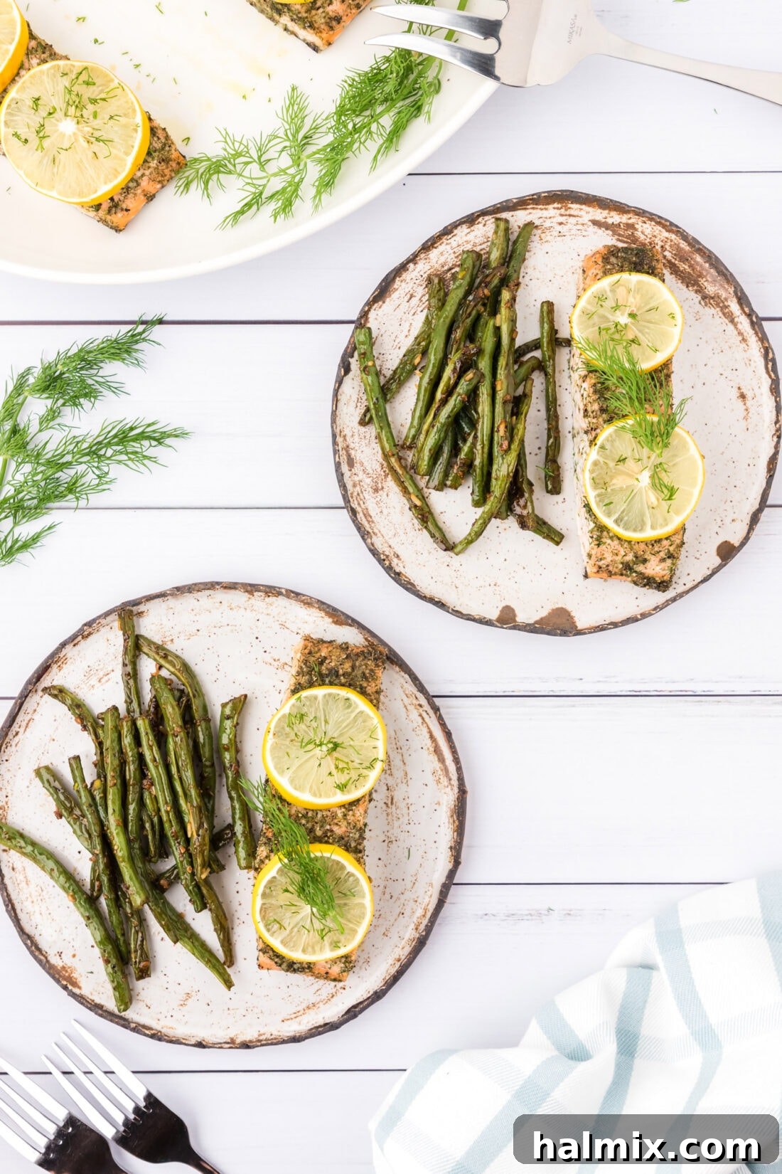 Smoked Salmon with Dill 2 Two plates of perfectly baked Dill Salmon served alongside fresh green beans, garnished with lemon wedges and a sprinkle of fresh dill.