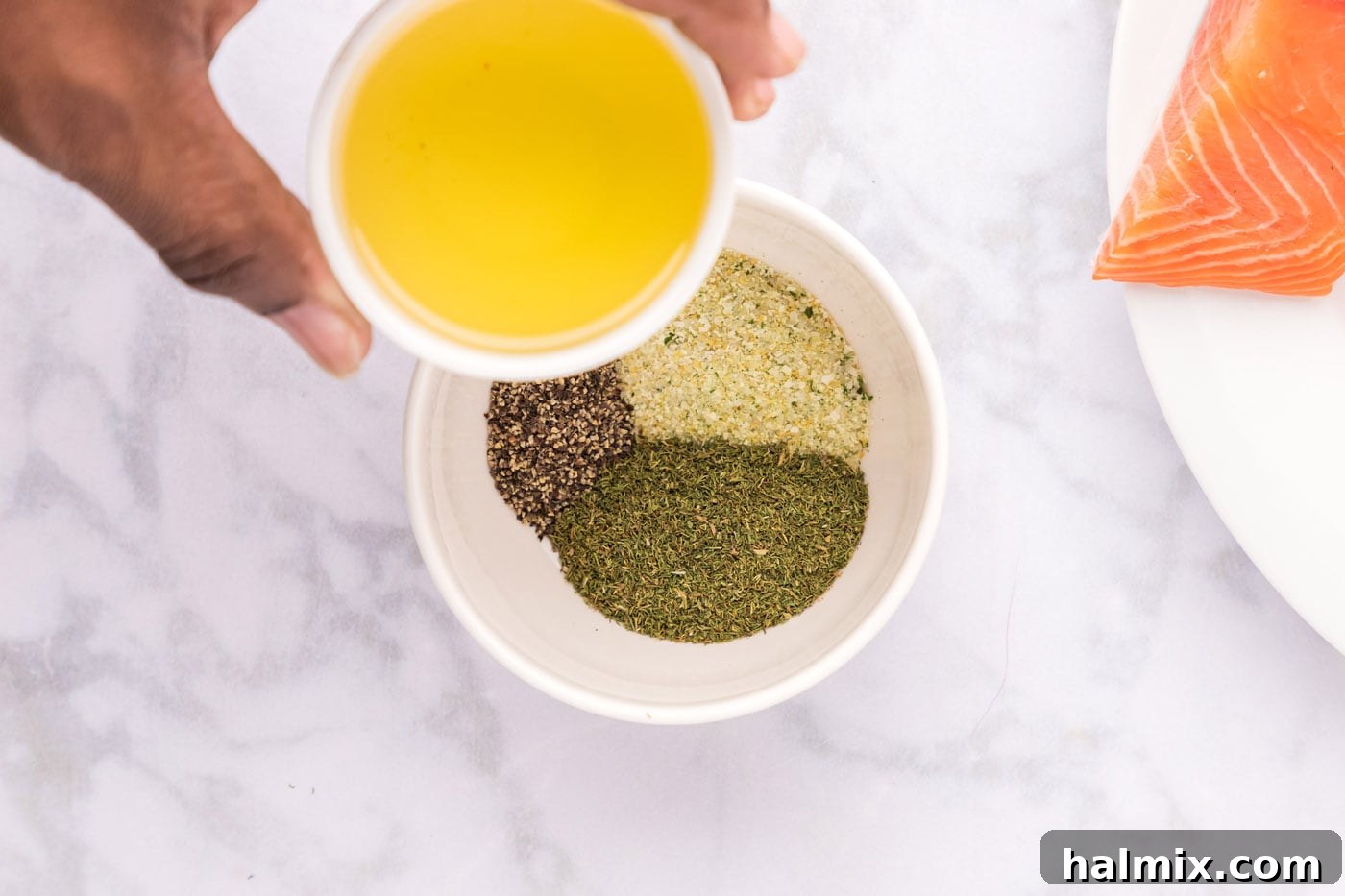 Smoked Salmon with Dill 5 Olive oil being poured into a bowl containing garlic salt, dried dill, and black pepper, ready to be mixed into a seasoning rub.