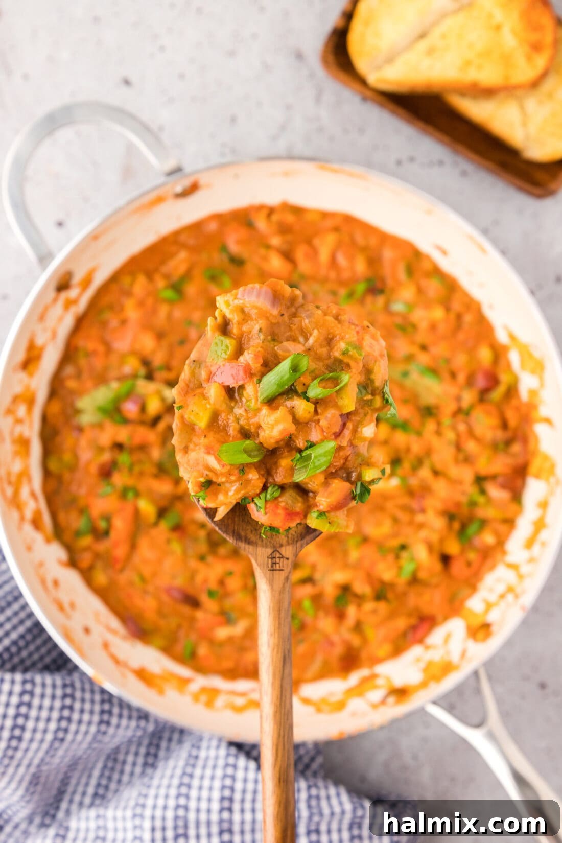 Spoonful of Crawfish Etoufee held above a skillet of Crawfish Etoufee, ready to be served