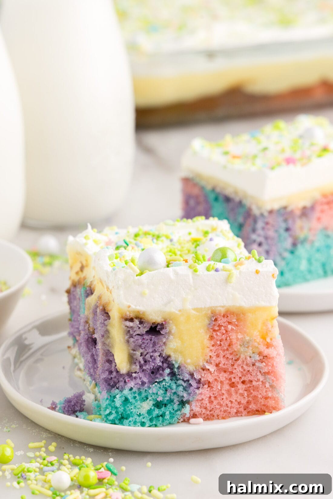Slice of Easter Poke Cake on a plate, showcasing pastel layers and creamy filling