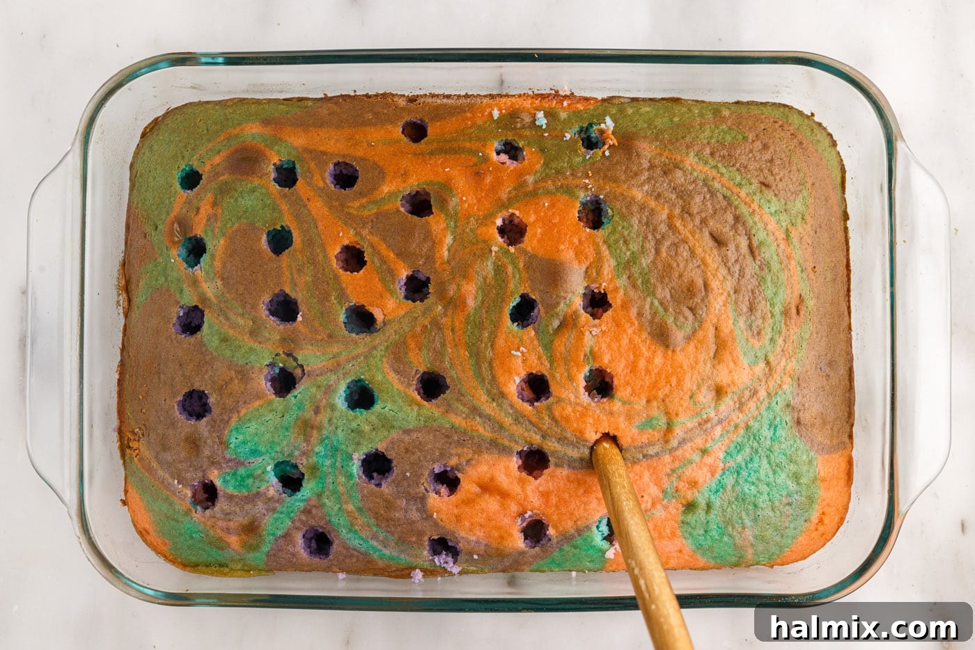 poking the top of a cake with a wooden spoon