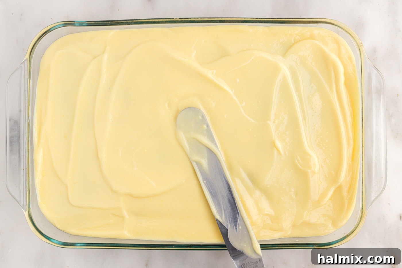 spreading vanilla pudding on top of cake