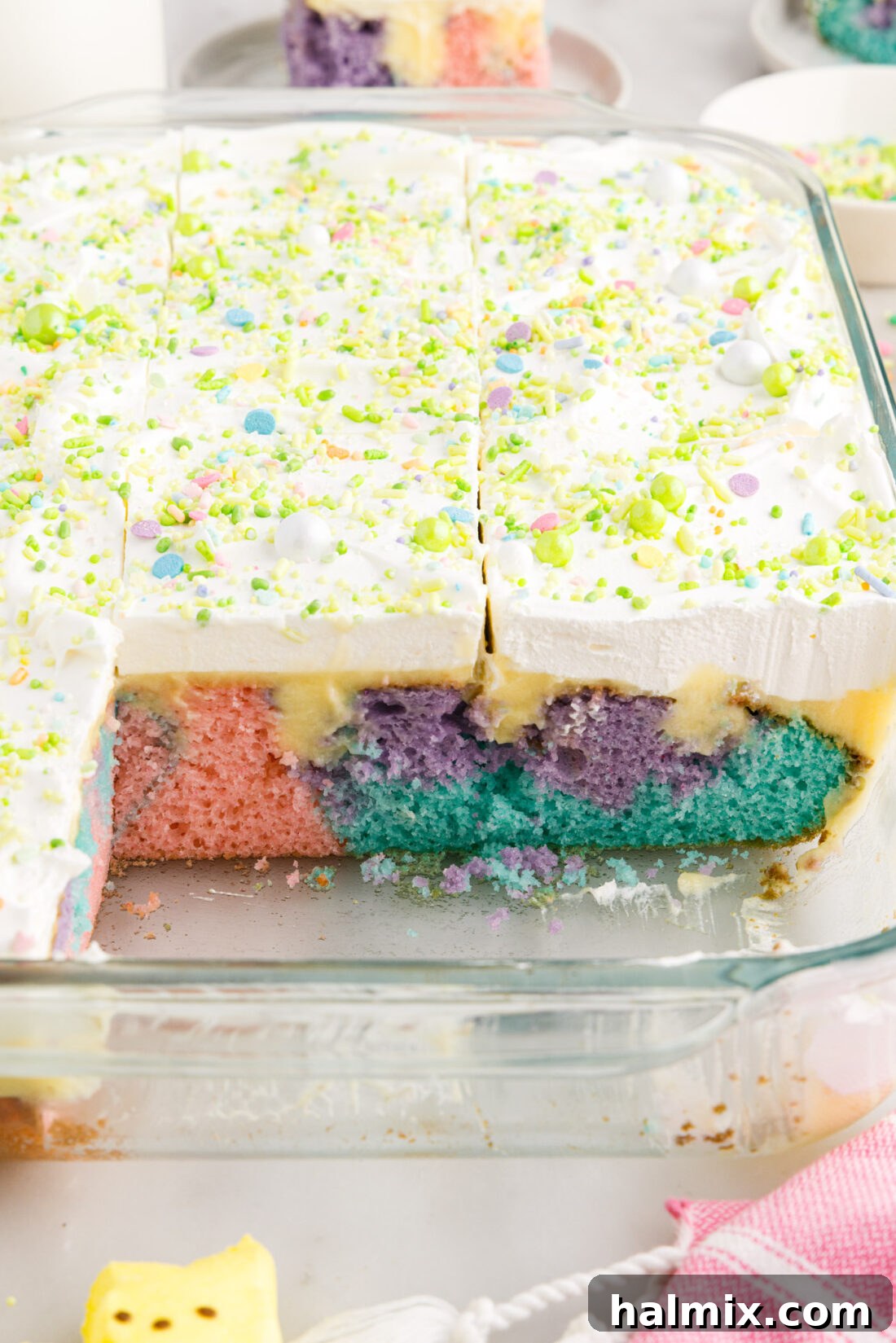 Easter Poke Cake in a 13x9 baking dish with two pieces removed, showing internal layers